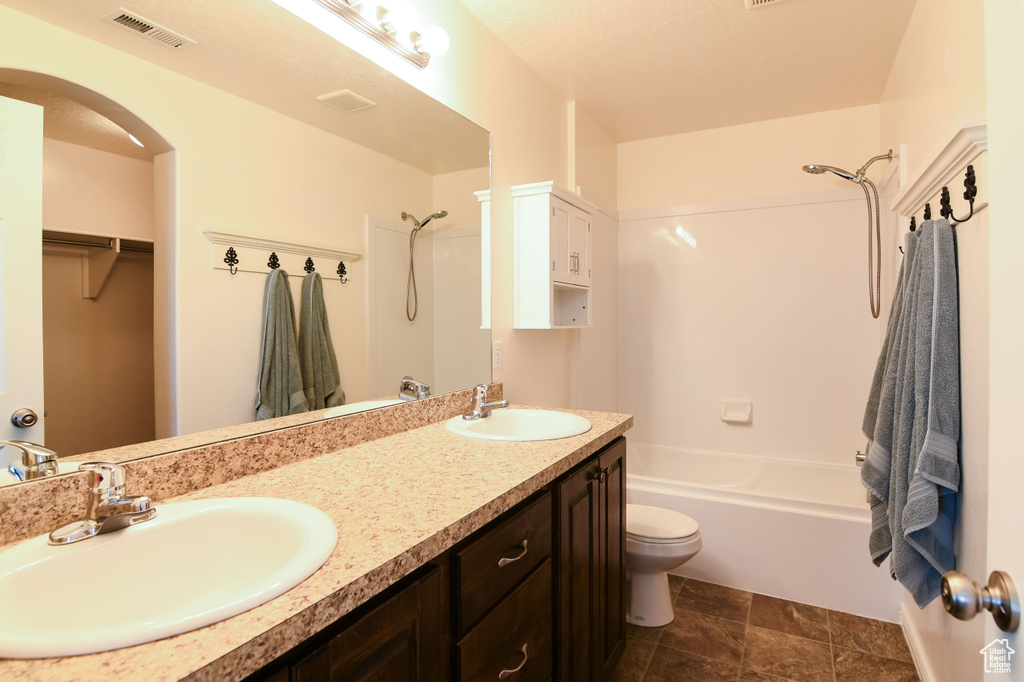 Full bathroom featuring double sink, bathing tub / shower combination, tile floors, toilet, and oversized vanity