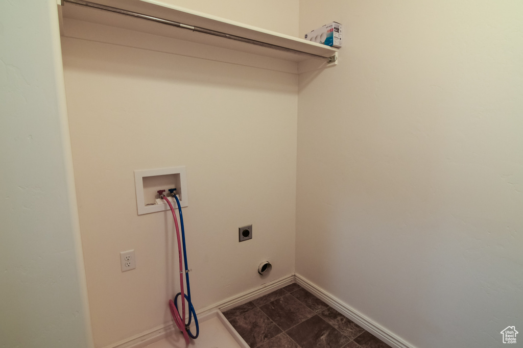 Washroom with dark tile flooring, hookup for a washing machine, and electric dryer hookup