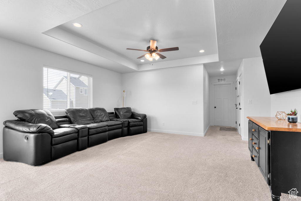 Living room featuring light colored carpet, ceiling fan, and a tray ceiling