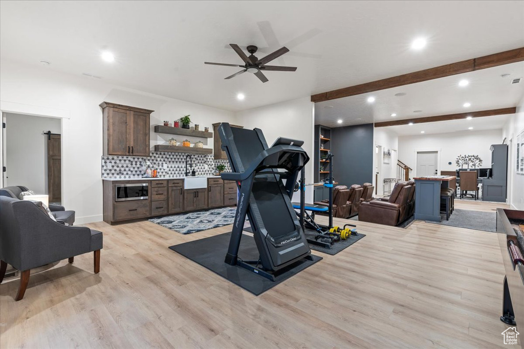 Exercise room featuring ceiling fan and light hardwood / wood-style flooring