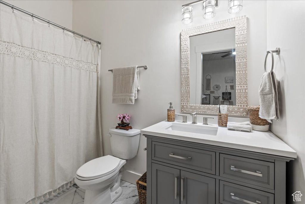 Bathroom featuring toilet, vanity with extensive cabinet space, tile flooring, and ceiling fan