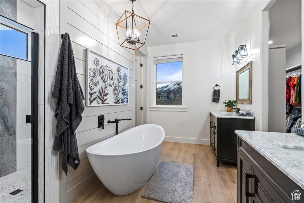 Bathroom featuring shower with separate bathtub, vanity, a chandelier, and hardwood / wood-style flooring