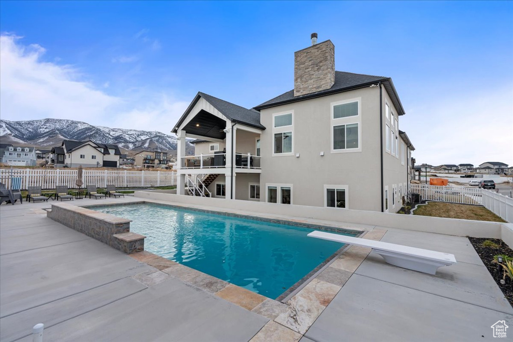 View of pool featuring a mountain view, a diving board, and a patio area