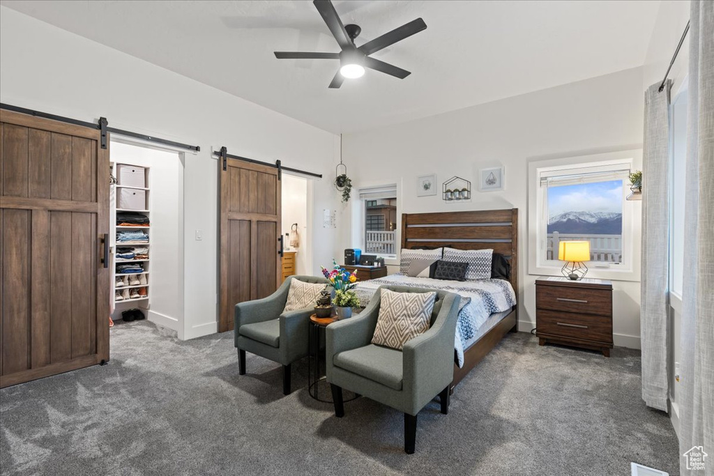 Carpeted bedroom featuring a barn door and ceiling fan