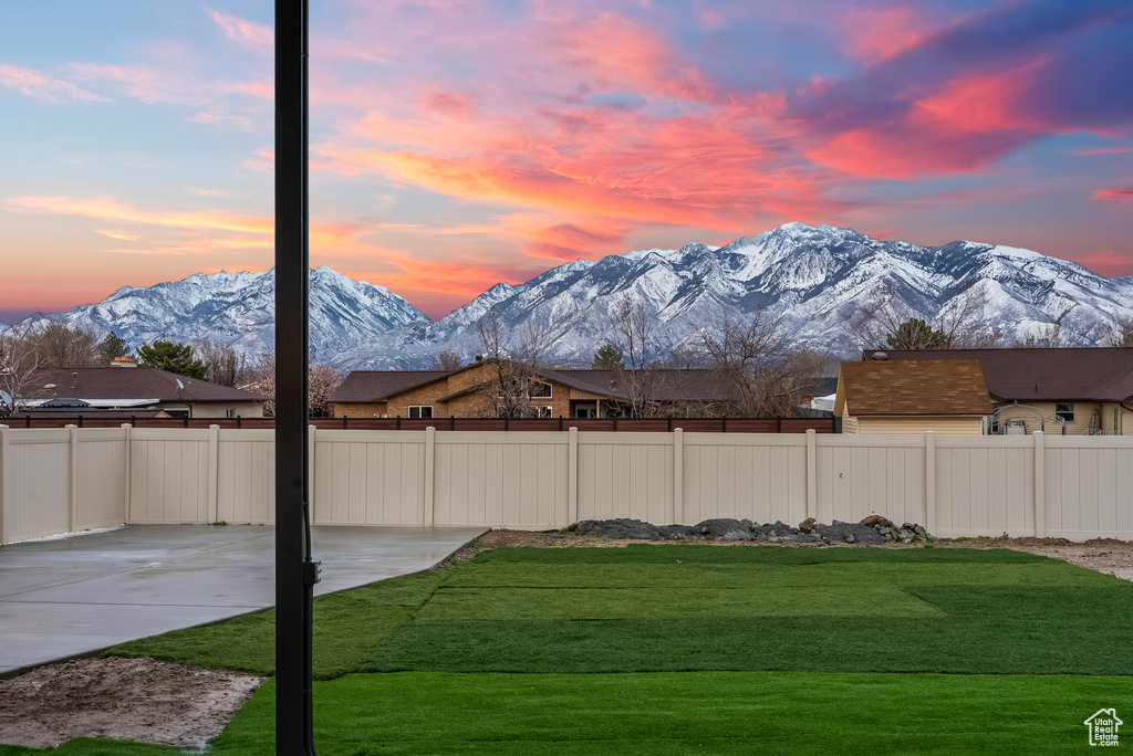 Yard at dusk featuring a mountain view and a patio area