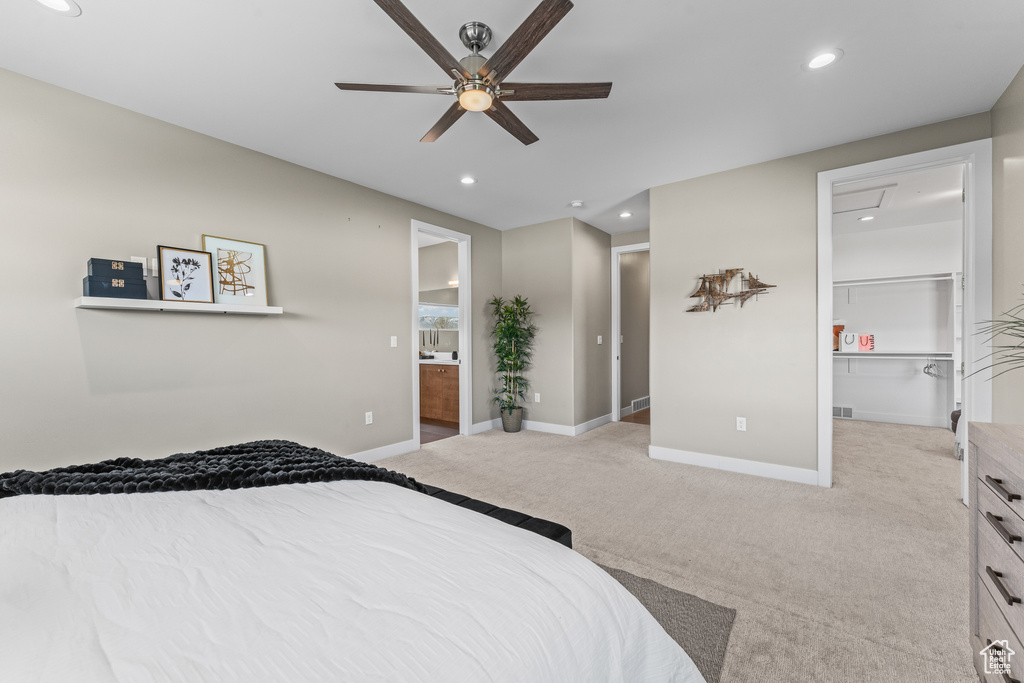 Bedroom with a closet, a walk in closet, ceiling fan, ensuite bath, and light colored carpet