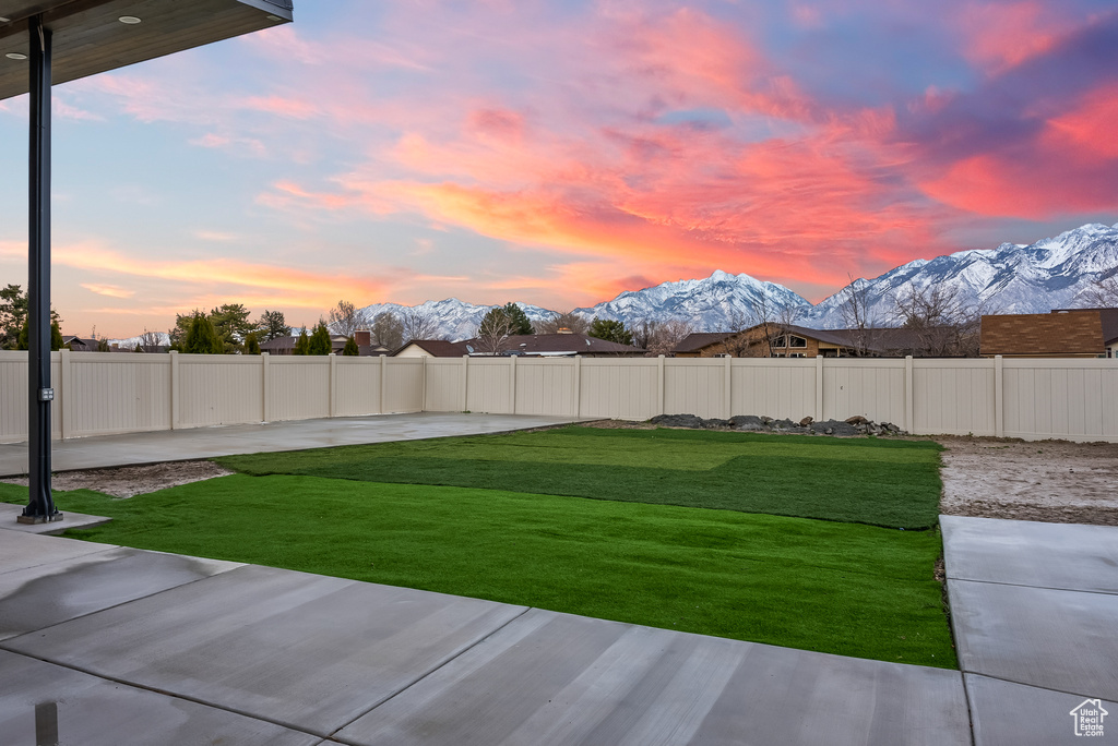 Yard at dusk featuring a mountain view and a patio
