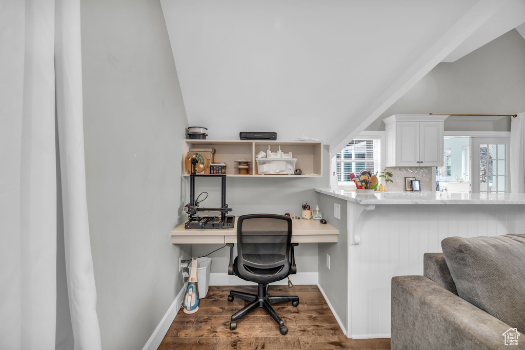 Home office with built in desk, wood-type flooring, and vaulted ceiling
