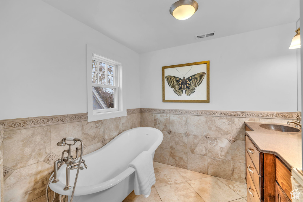 Bathroom with vanity, tile flooring, a washtub, and tile walls