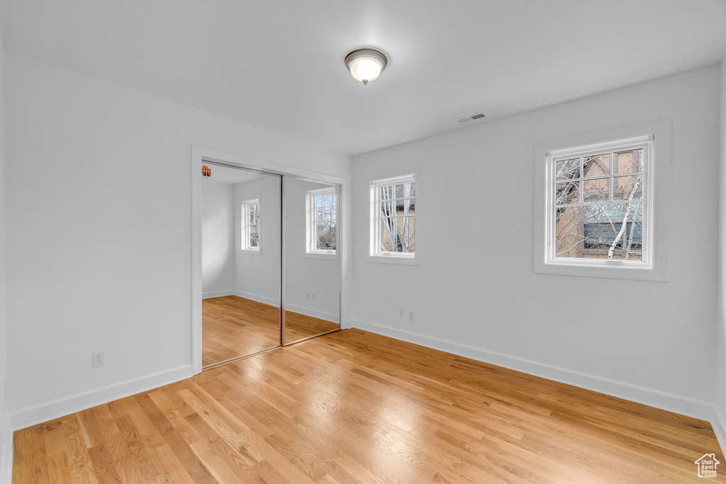 Unfurnished bedroom with multiple windows, a closet, and light hardwood / wood-style flooring