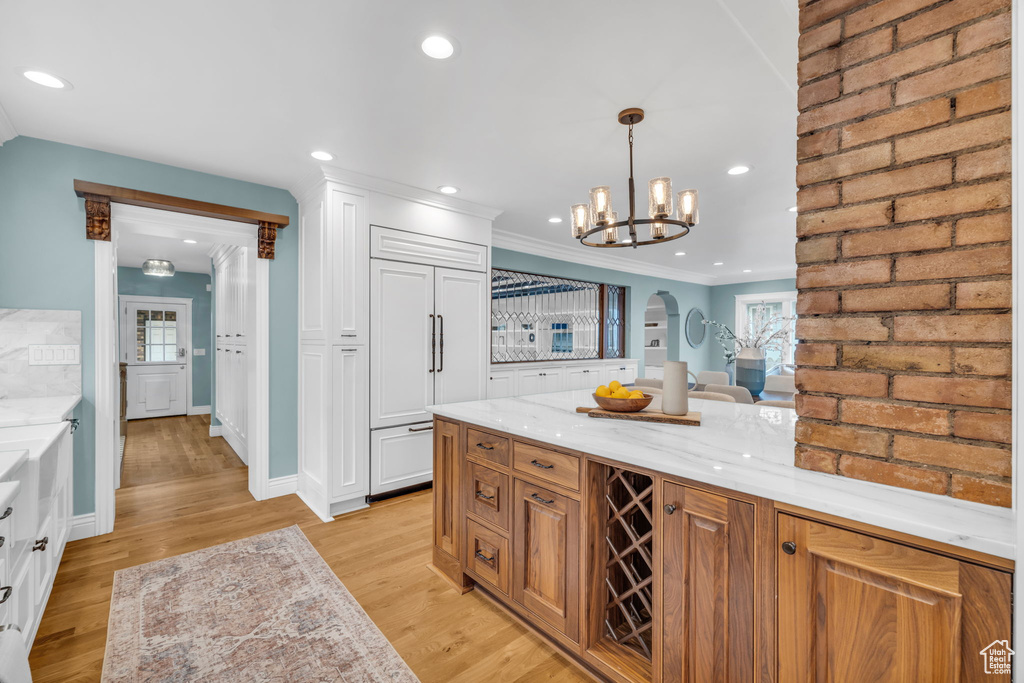 Kitchen featuring light hardwood / wood-style floors, ornamental molding, pendant lighting, and a chandelier