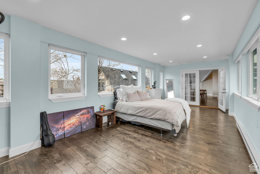 Bedroom with french doors, baseboard heating, dark hardwood / wood-style flooring, and multiple windows