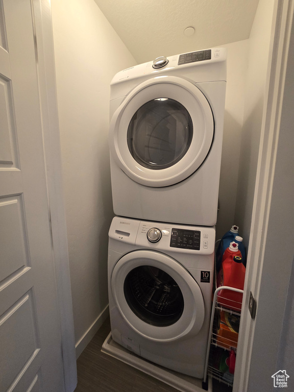 Laundry area featuring stacked washing maching and dryer and dark hardwood / wood-style floors