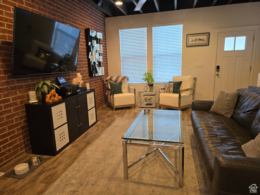 Living room featuring brick wall and dark hardwood / wood-style flooring