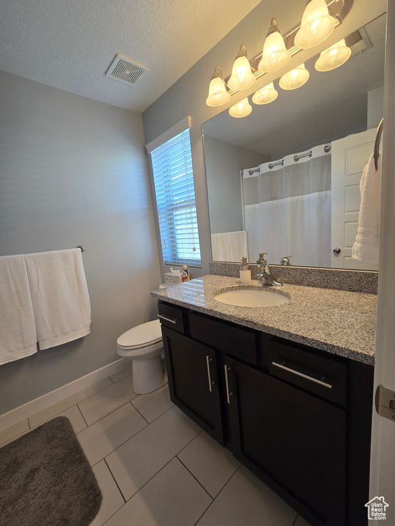 Bathroom featuring oversized vanity, toilet, a textured ceiling, and tile floors