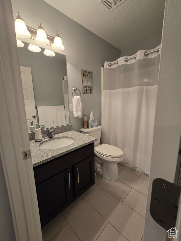 Bathroom with vanity, a textured ceiling, tile floors, and toilet