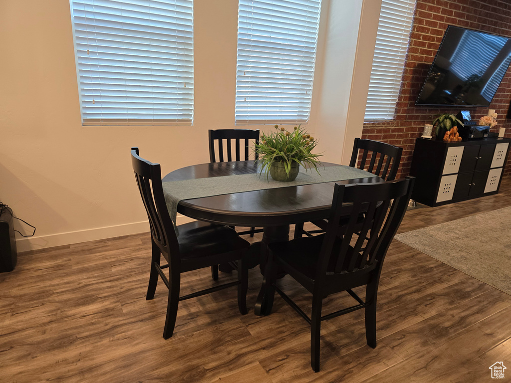 Dining area featuring brick wall and dark wood-type flooring