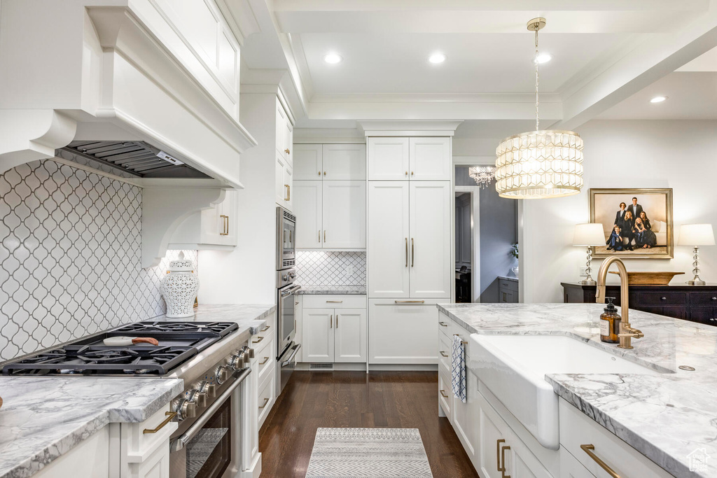 Kitchen featuring pendant lighting, appliances with stainless steel finishes, a chandelier, custom range hood, and tasteful backsplash