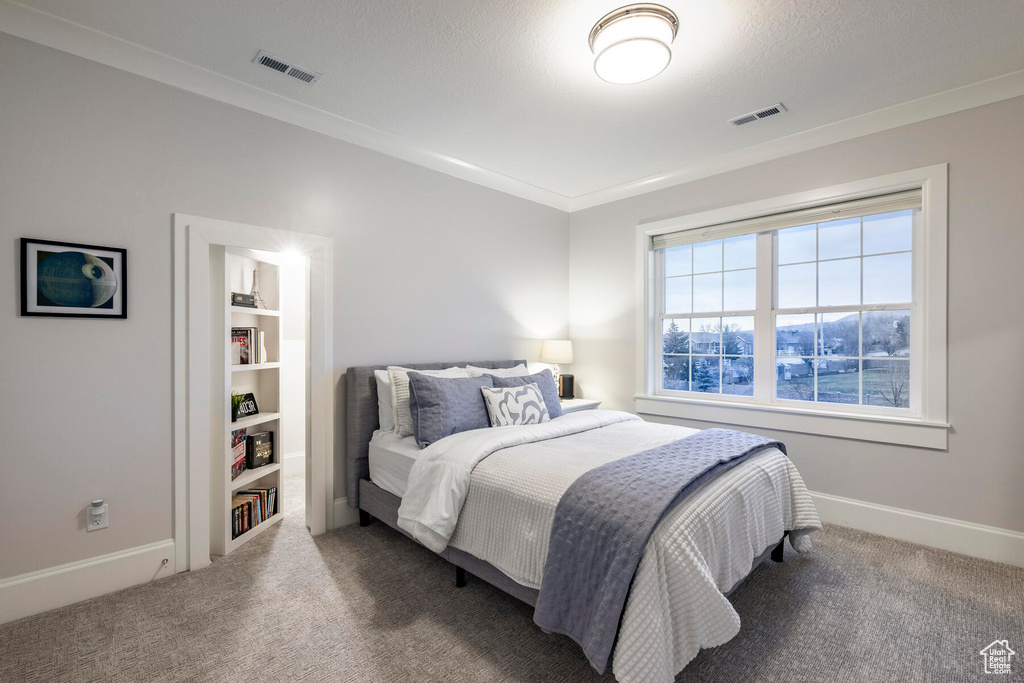 Bedroom featuring crown molding and dark carpet