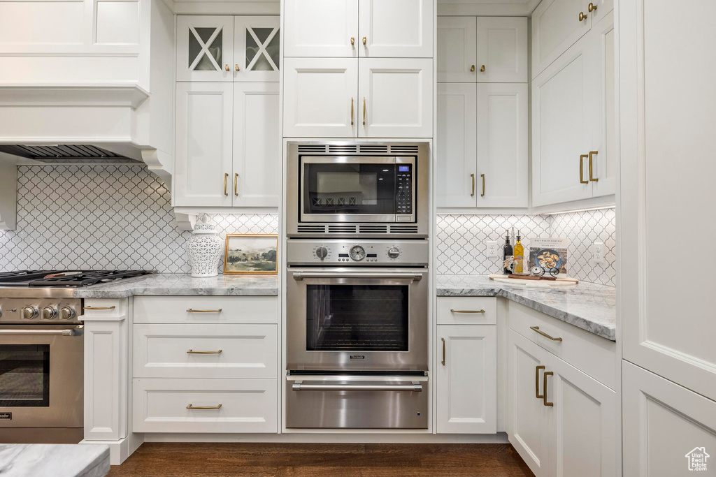 Kitchen with white cabinets, backsplash, and stainless steel appliances