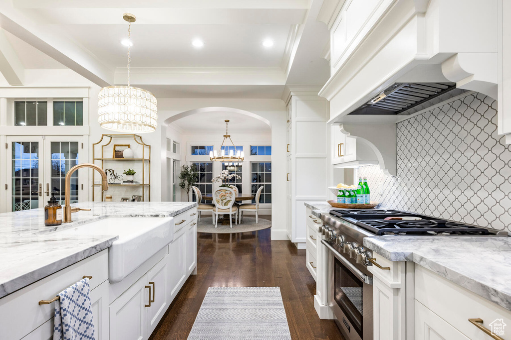 Kitchen with decorative light fixtures, an inviting chandelier, stainless steel range, tasteful backsplash, and french doors