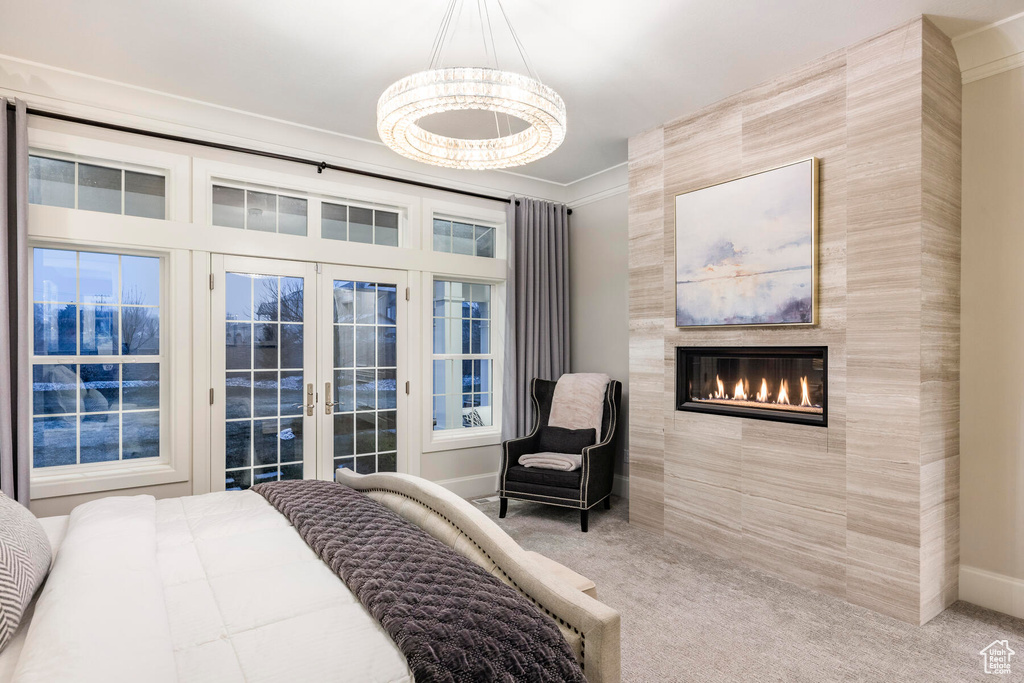 Bedroom with crown molding, french doors, an inviting chandelier, and light colored carpet