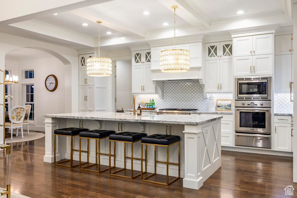 Kitchen featuring an island with sink, an inviting chandelier, stainless steel appliances, and dark wood-type flooring