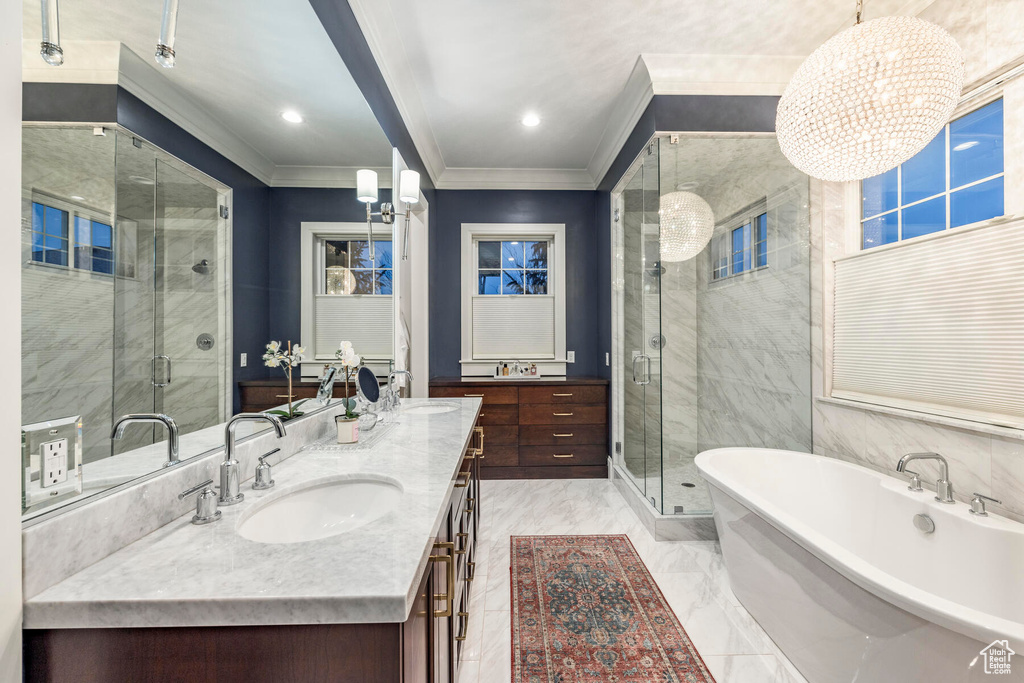 Bathroom featuring a notable chandelier, ornamental molding, shower with separate bathtub, dual bowl vanity, and tile floors