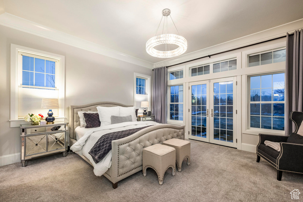 Carpeted bedroom featuring access to exterior, a notable chandelier, french doors, and ornamental molding