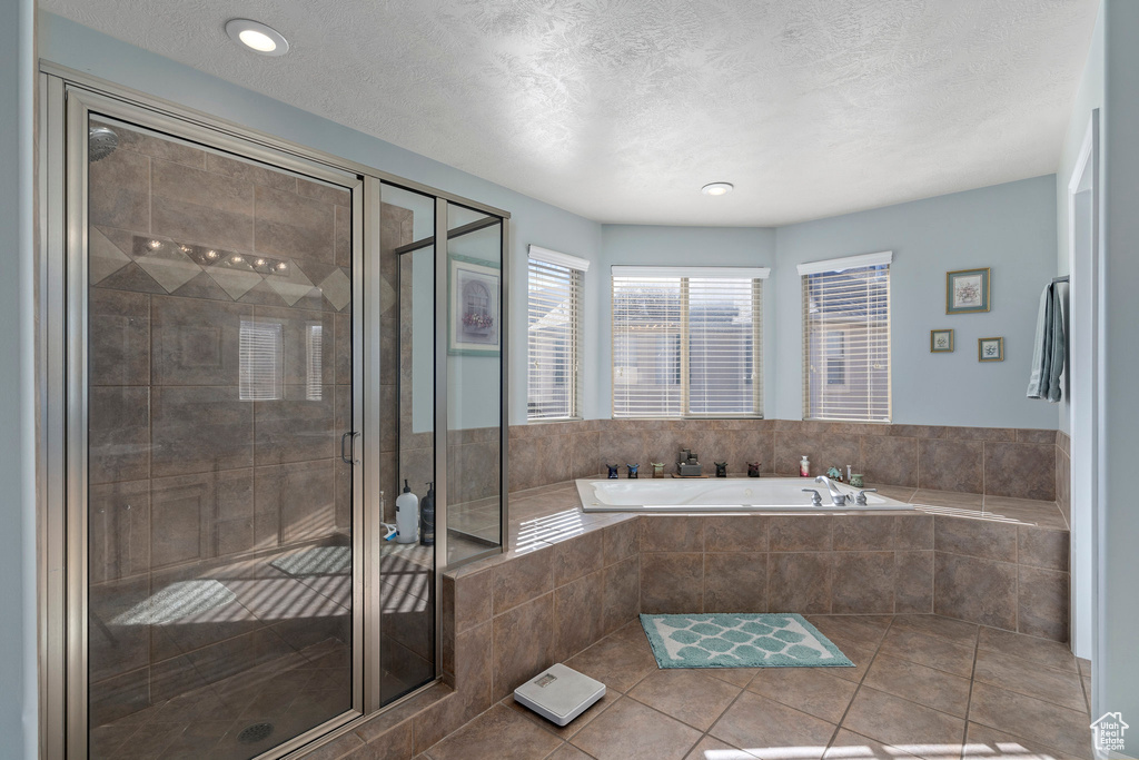 Bathroom featuring tile floors, separate shower and tub, and a textured ceiling