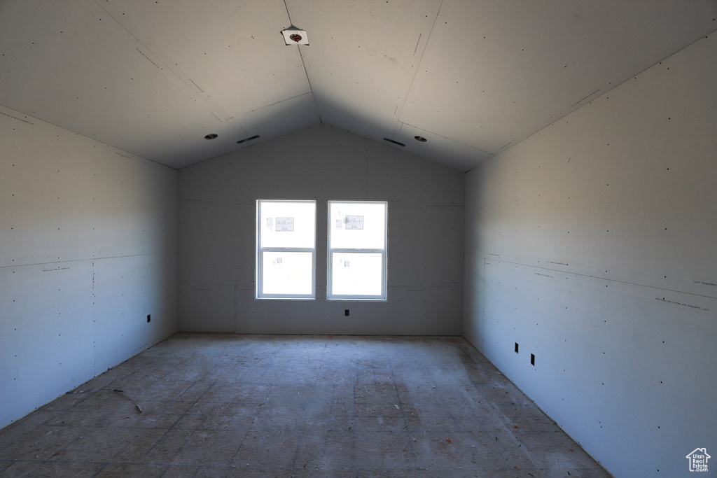 Empty room featuring vaulted ceiling