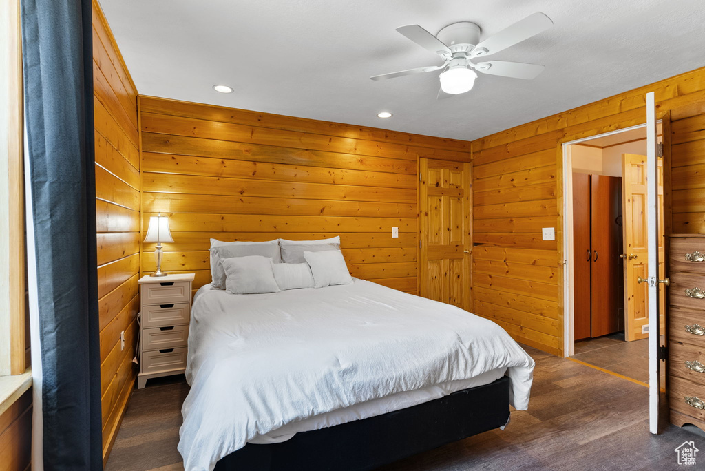 Bedroom featuring wooden walls, ceiling fan, and dark wood-type flooring
