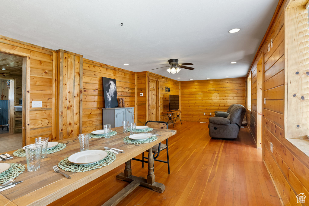 Dining area featuring wood walls, light hardwood / wood-style floors, and ceiling fan