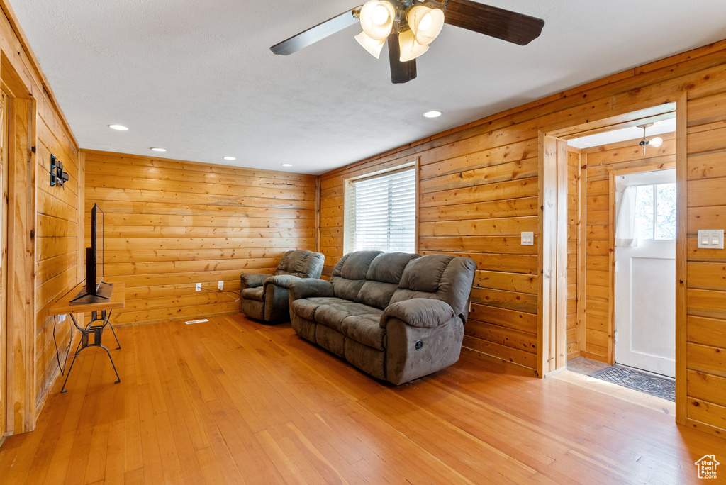 Living room featuring wooden walls, light hardwood / wood-style floors, and ceiling fan