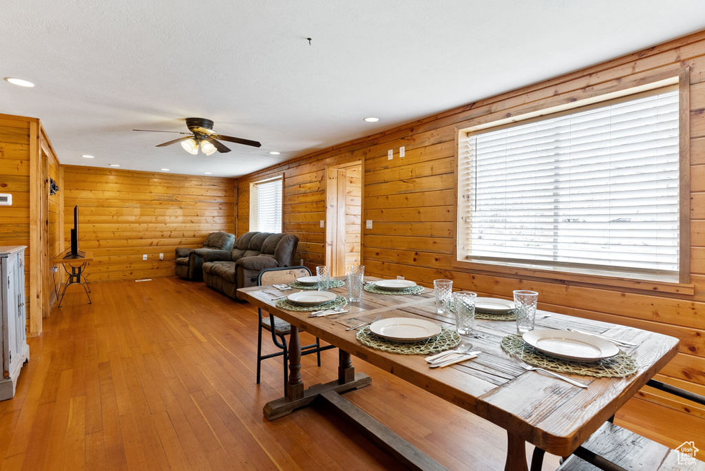 Dining space with wood walls, ceiling fan, and light hardwood / wood-style flooring