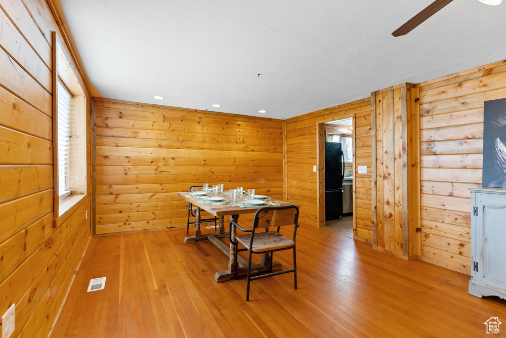 Dining space featuring wooden walls, light hardwood / wood-style floors, and ceiling fan