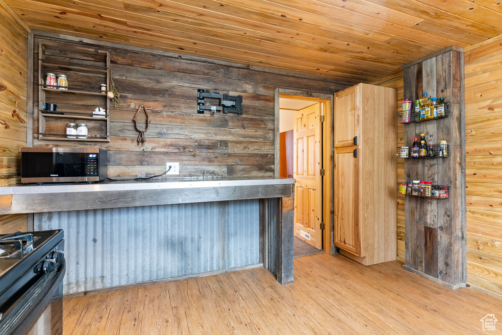 Kitchen with wooden walls, light hardwood / wood-style floors, and black range