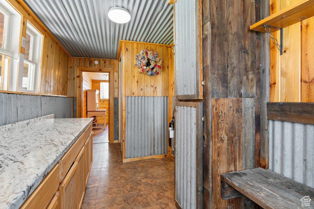 Kitchen featuring wooden walls, dark tile flooring, and light stone countertops