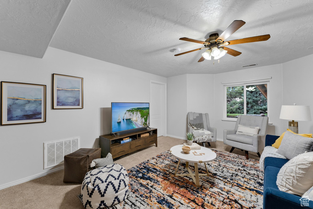 Living room featuring light carpet, a textured ceiling, and ceiling fan