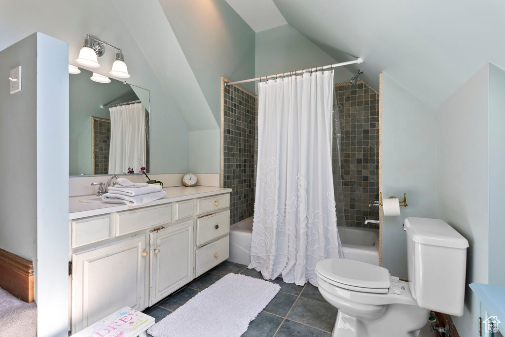 Full bathroom with tile flooring, lofted ceiling, toilet, vanity, and shower / bathtub combination with curtain