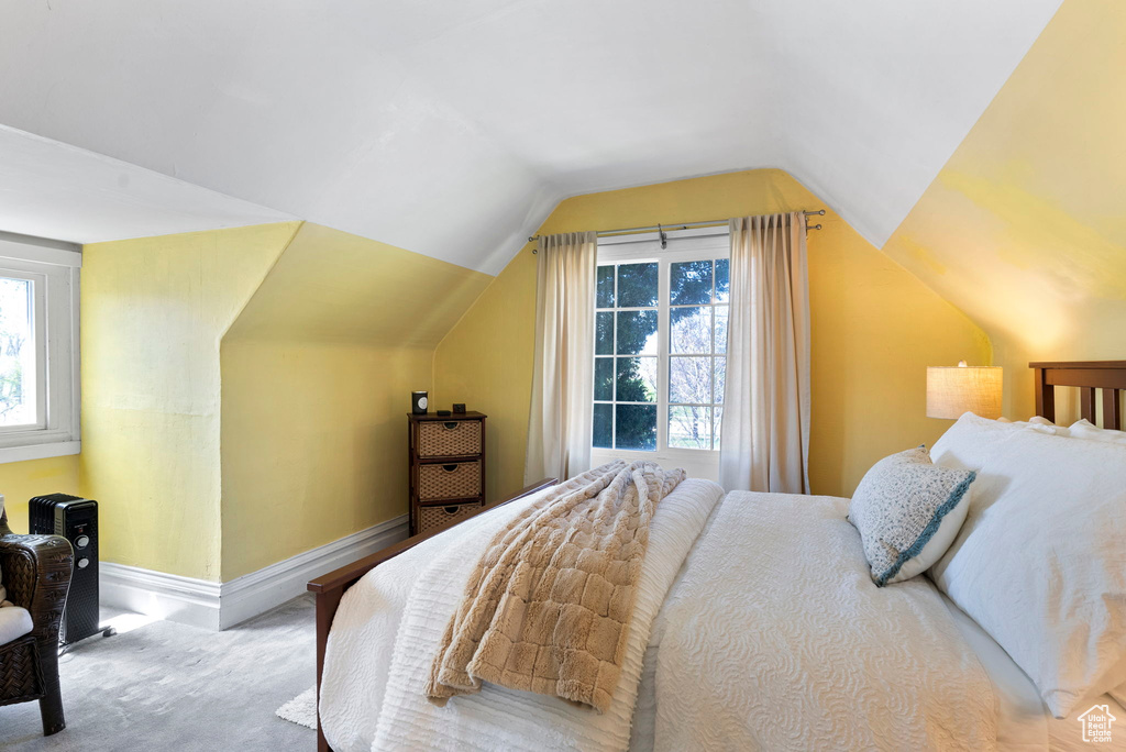 Carpeted bedroom featuring vaulted ceiling and multiple windows