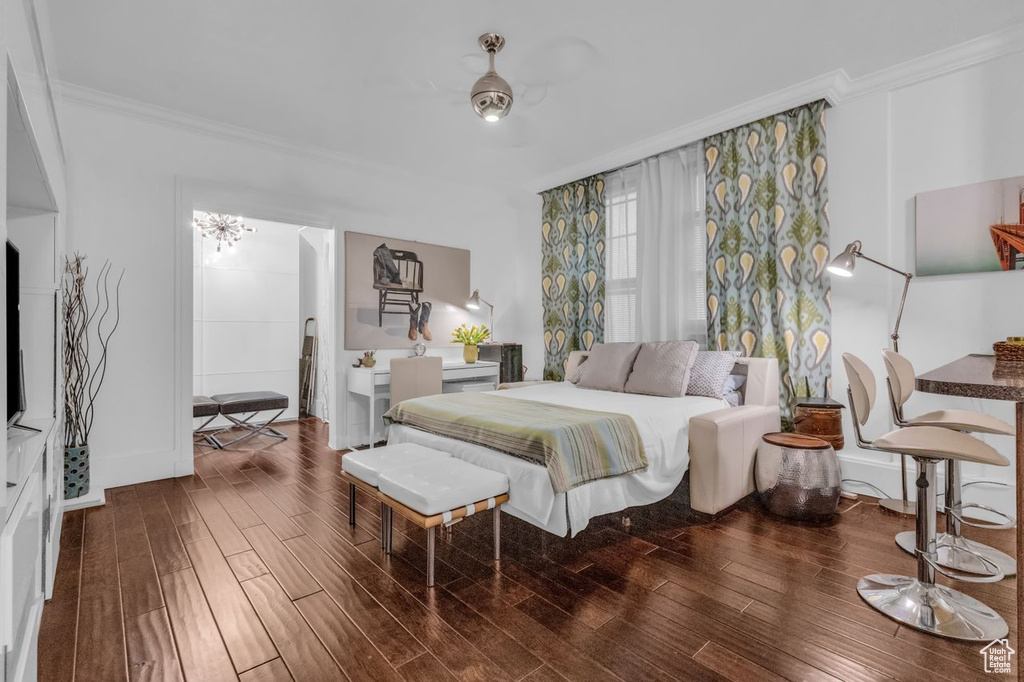 Bedroom with ceiling fan with notable chandelier, dark hardwood / wood-style flooring, and ornamental molding