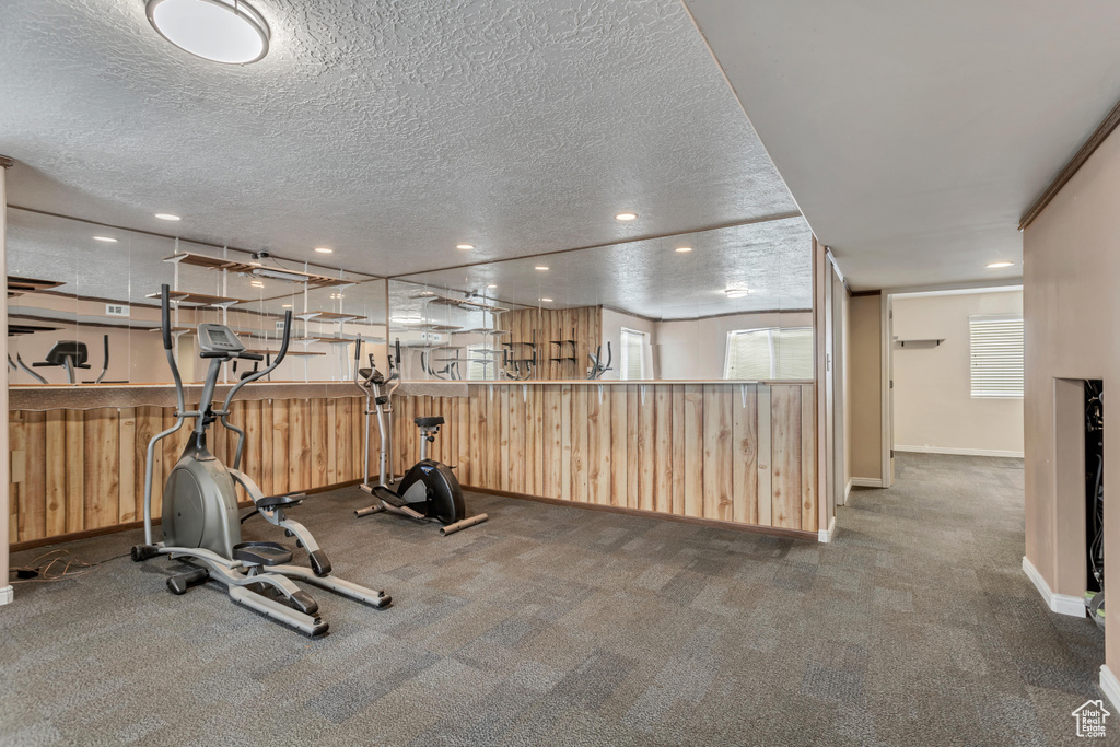 Exercise room with a textured ceiling and dark colored carpet