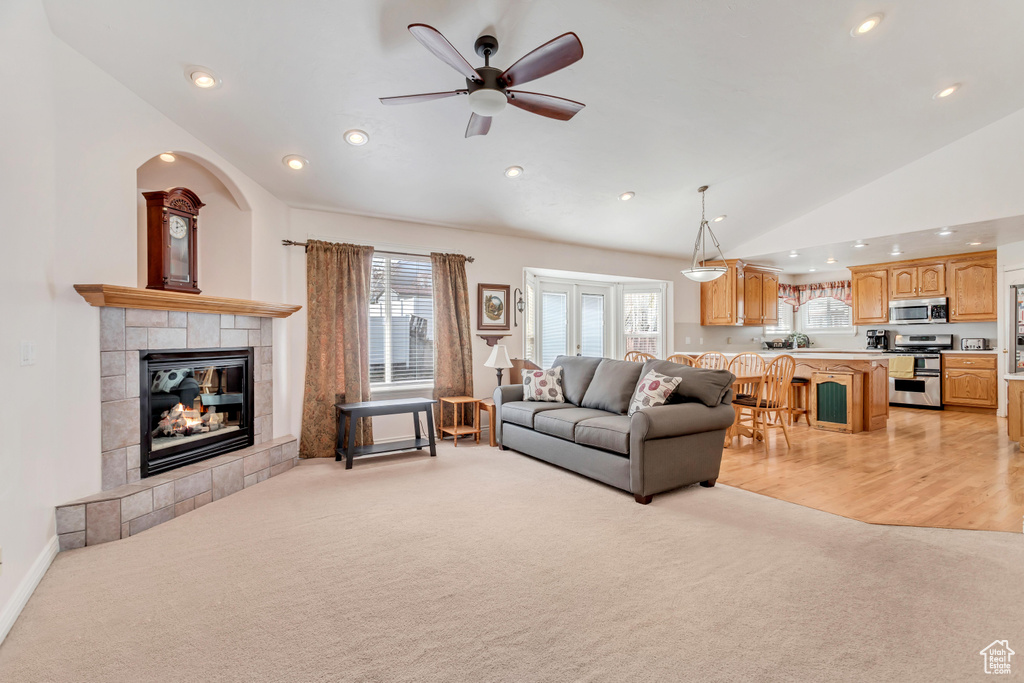 Living room featuring light carpet, high vaulted ceiling, ceiling fan, and a fireplace