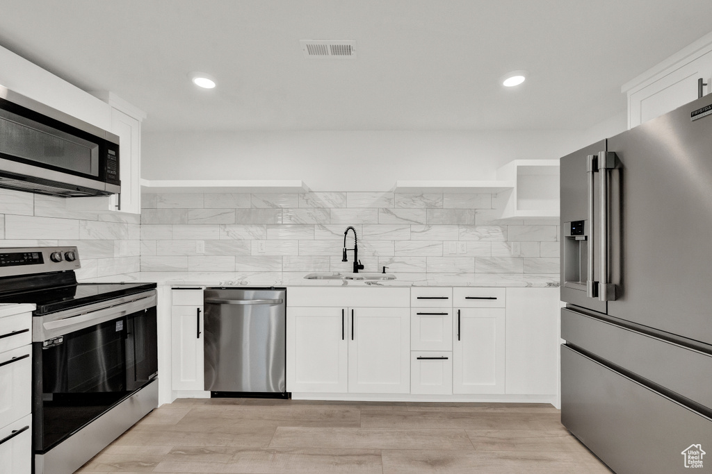 Kitchen featuring backsplash, stainless steel appliances, light wood-type flooring, and sink