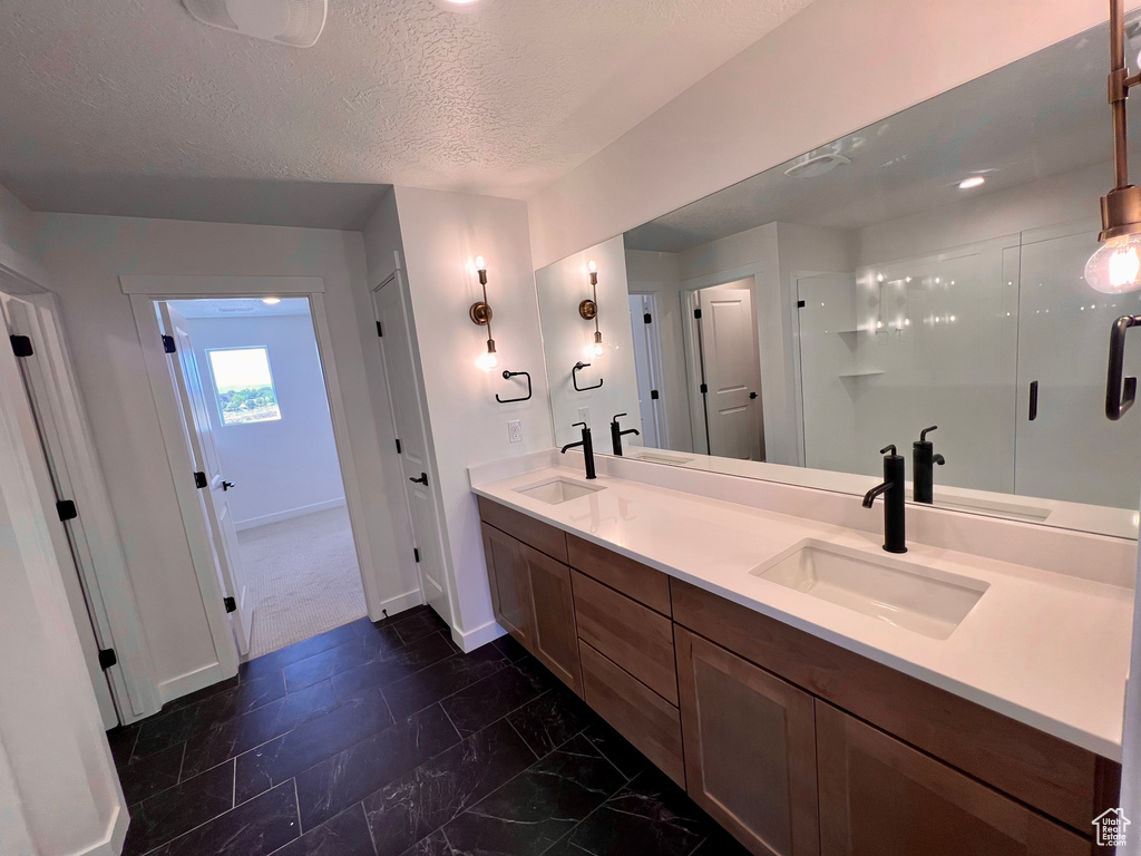 Bathroom with an enclosed shower, a textured ceiling, tile floors, and dual bowl vanity