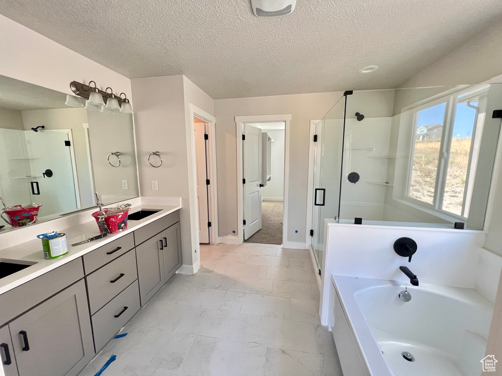 Bathroom with vanity, a textured ceiling, tile flooring, and separate shower and tub