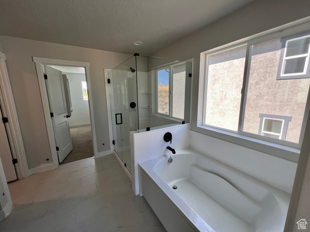 Bathroom featuring a textured ceiling, plenty of natural light, tile flooring, and independent shower and bath