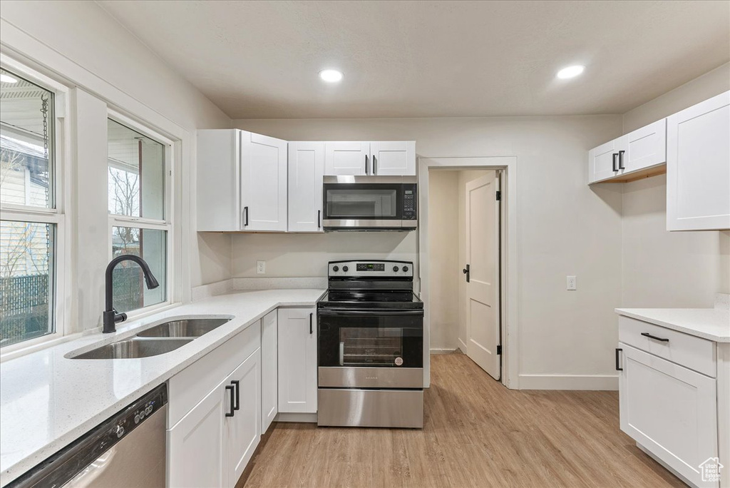 Kitchen with white cabinetry, light hardwood / wood-style floors, stainless steel appliances, and plenty of natural light