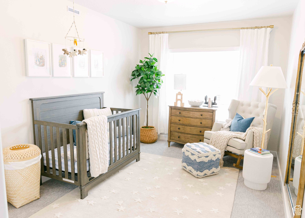 Bedroom featuring a notable chandelier, light carpet, and a nursery area